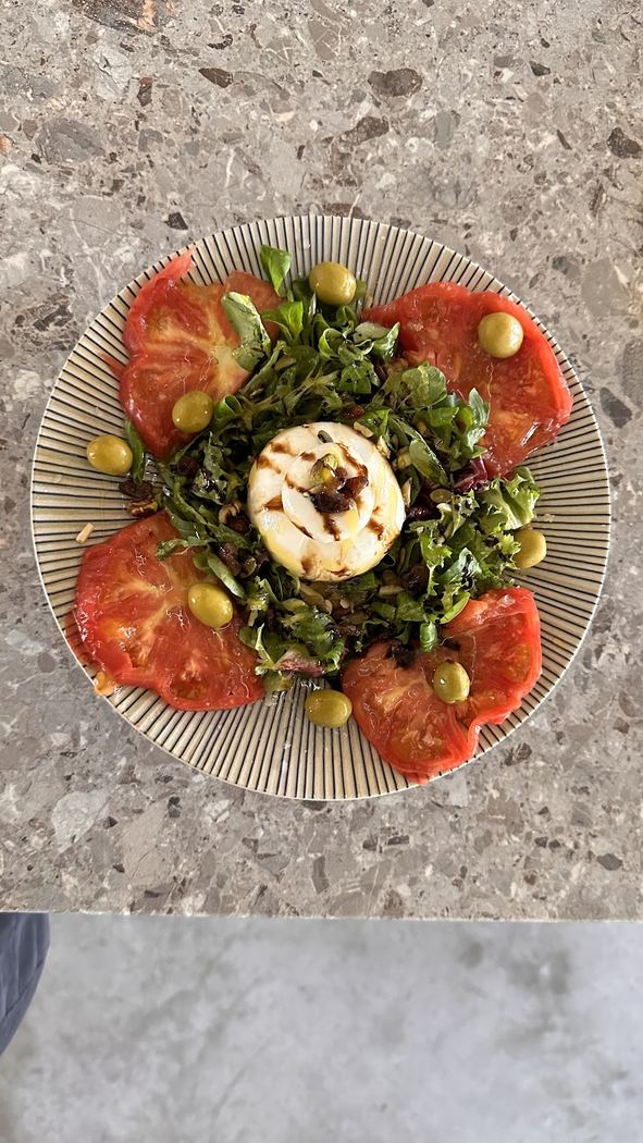 Ensalada fresca de tomate natural con burrata cremosa y aceitunas.